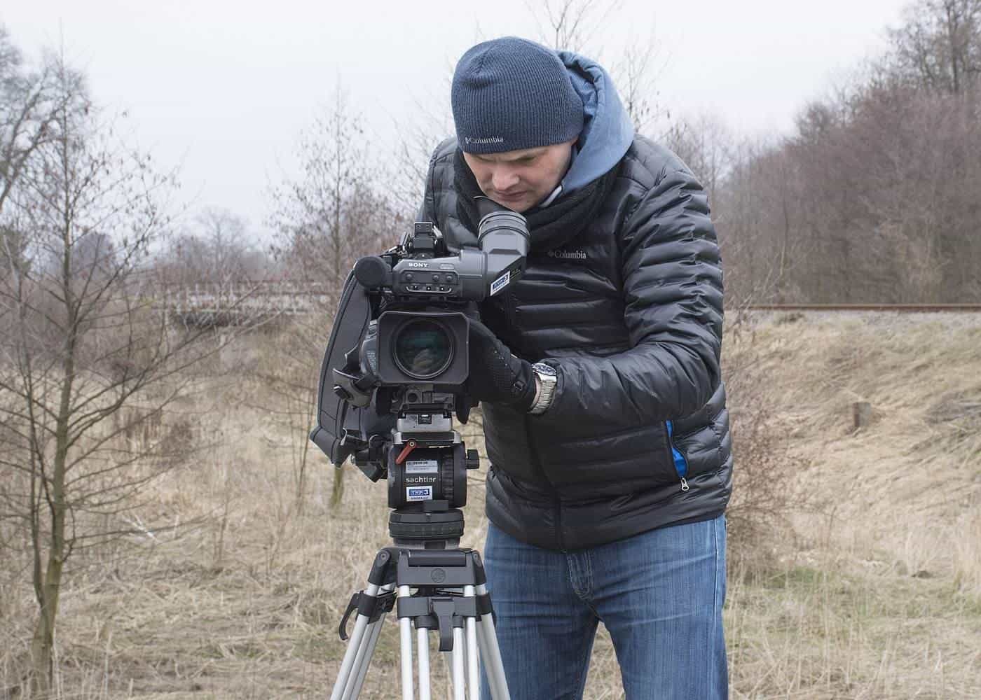 A camera operator filming with a professional video camera