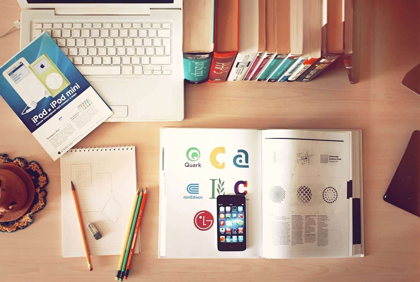 A laptop, phone, books and pencils on a desk